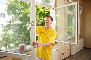 Junger Auszubildender lackiert ein Fenster