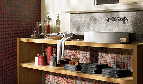 Waschtisch aus Holz mit moderner Aufsatzkeramik und offenem Regal, gestaltet mit rot grauem JASBA Mosaik, ergänzt durch dekorative Accessoires und Wandfliesen mit Ornamentstruktur.