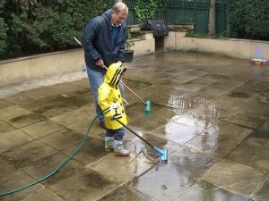 Mann und Kind reinigen Sandsteinboden mit Wasser