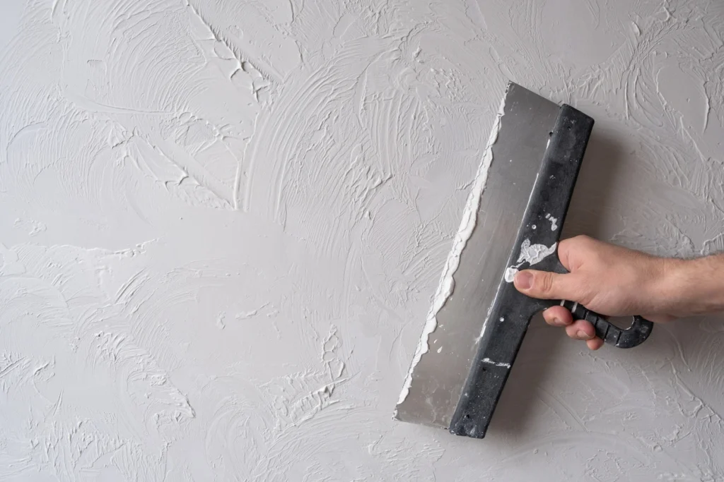 Strukturputz wird mit Kelle auf Wand aufgetragen.