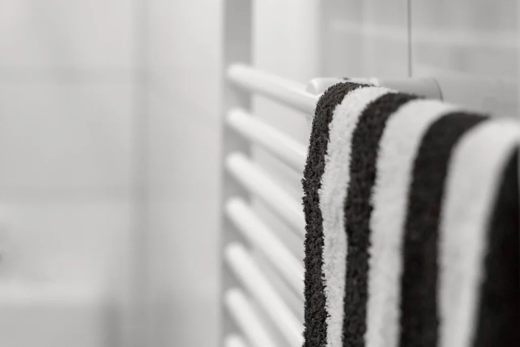 Schwarz-weiß gestreiftes Handtuch hängt an einem weißen Röhrenheizkörper im Badezimmer.