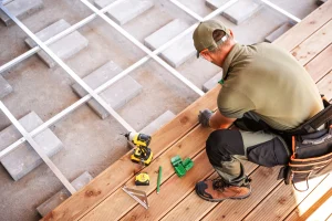 Bauarbeiter verlegt Terrassendielen mit Werkzeugen.