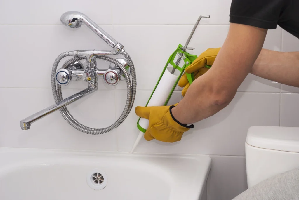 Erneuern einer Silikonfuge am Rand einer Badewanne mit einer Kartuschenpresse.
