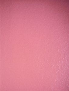 Einfarbige rosa Wand mit einer leicht strukturierten Oberfläche.
