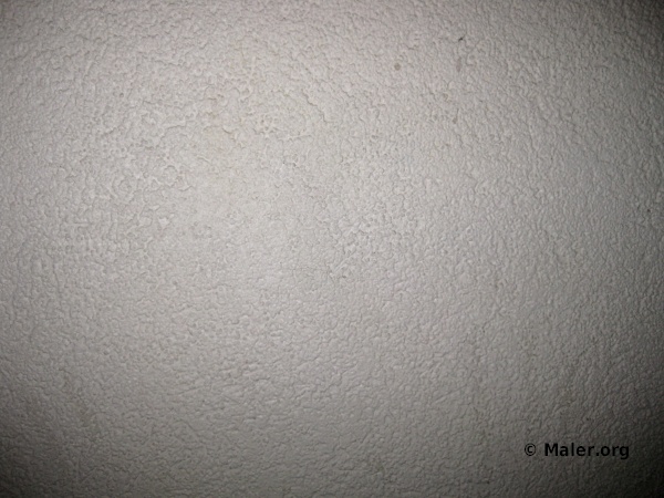 Texturierte weiße Wand mit rauer Oberfläche. Die Struktur der Wand zeigt ein ungleichmäßiges Muster aus kleinen Erhebungen und Vertiefungen. In der unteren rechten Ecke steht "© Maler.org".