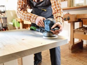 Schreiner schleift einen Küchentisch aus Holz