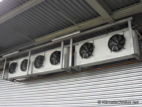 Industrie-Kühlventilatoren an der Decke montiert, bestehend aus fünf Einheiten mit jeweils einem Lüfter. Die Ventilatoren sind in einem rechteckigen Metallrahmen installiert und dienen zur Abführung von Wärme in einer industriellen Umgebung.