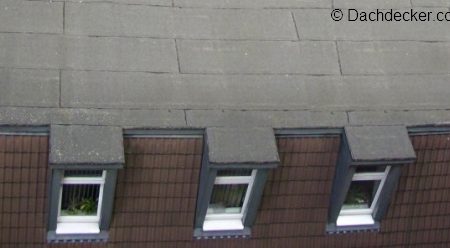Schrägdach mit dunkler Dachpappe und drei kleinen Gaubenfenstern, die bündig mit dem Dachabschluss integriert sind.