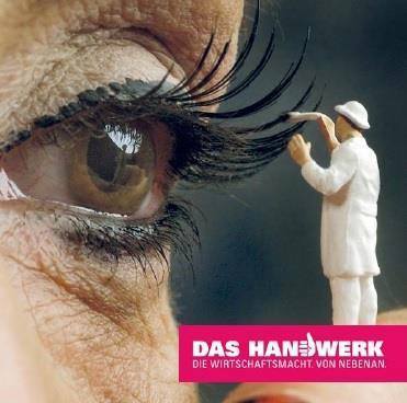 Ein riesiges Auge ist zu sehen, daneben steht eine winzige Figur in Malerbekleidung, die die oberen Wimpern zu streichen scheint. Unten rechts das Logo "Das Handwerk" mit dem Slogan "Die Wirtschaftsmacht. Von nebenan."