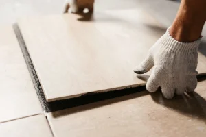 Eine neue Fliese wird von Hand in eine Lücke im Fliesenbett eingesetzt.