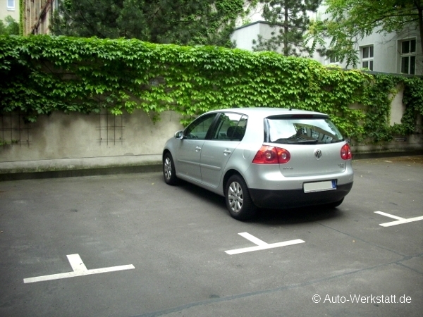 Der Check von Gebrauchtwagen wird in mehreren Schritten durchgeführt. Silberner Volkswagen Golf steht auf einem Parkplatz mit einer Wand voller grüner Kletterpflanzen im Hintergrund. Die Umgebung wirkt ruhig und die Fläche ist leer bis auf das geparkte Auto.
