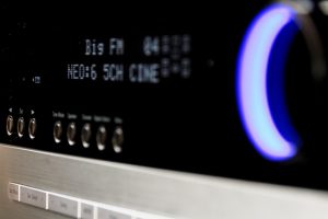 Nahaufnahme eines SAT-Receivers mit digitaler Anzeige und mehreren Bedientasten. Ein großer, blau beleuchteter Einstellregler ist deutlich sichtbar.