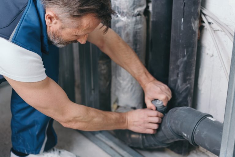 Sanitärinstallateur prüft Dichtung von Abwasserrohren