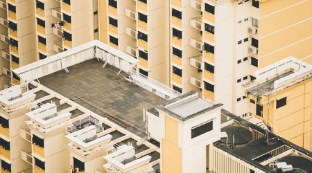 Dachansicht eines modernen, hellgelben Wohnhochhauses mit Flachdach, begehbarer Dachterrasse und mehreren technischen Aufbauten wie Klimaanlagen und Lüftungssystemen.