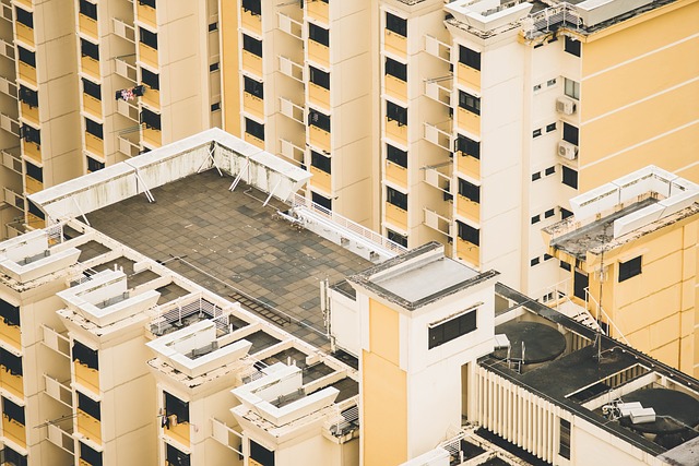 Dachansicht eines modernen, hellgelben Wohnhochhauses mit Flachdach, begehbarer Dachterrasse und mehreren technischen Aufbauten wie Klimaanlagen und Lüftungssystemen.