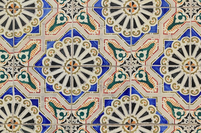 Bunte Wandfliesen mit traditionellem maurischem Muster in Blau, Grün, Orange und Schwarz, mit floralen und geometrischen Elementen in regelmäßiger Anordnung.