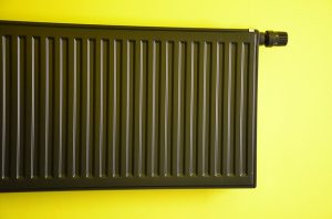 Schwarzer Heizkörper an einer gelben Wand