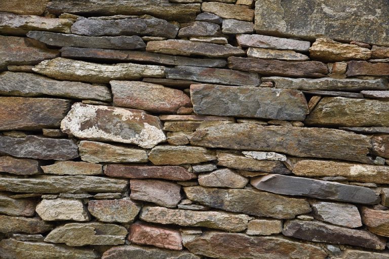 Detailansicht einer naturbelassenen Trockenmauer aus unregelmäßig geschichteten Natursteinen im Gartenbau.