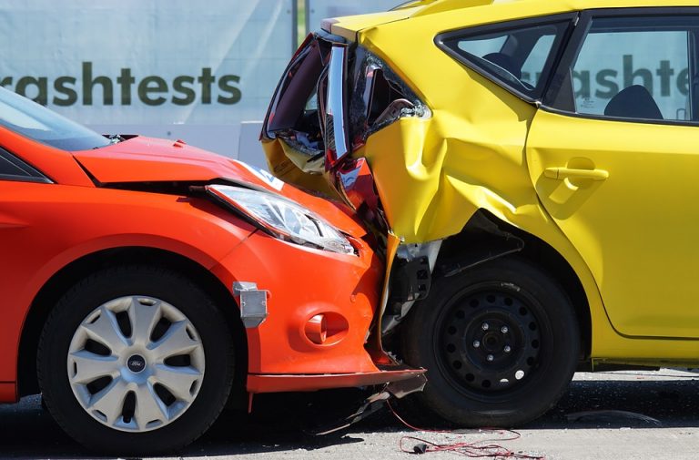 Auffahrunfall zwischen einem roten und einem gelben Auto mit deutlich sichtbaren Karosserieschäden.