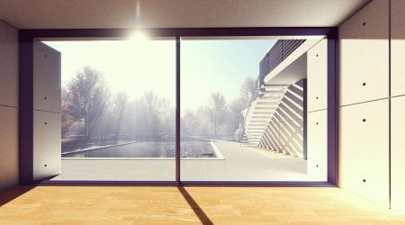 Großflächige bodentiefe Fenster in einem modernen Wohnhaus mit Blick auf eine sonnige Terrasse und einen Poolbereich. Die Fenster sorgen für maximale Tageslichtnutzung und schaffen fließende Übergänge zwischen Innen- und Außenraum.
