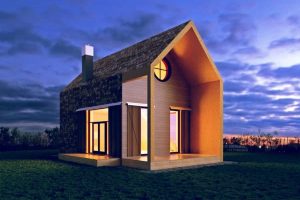 Modernes Tiny House mit asymmetrischem Satteldach und rundem Fenster, beleuchtet bei Sonnenuntergang, auf freiem Grundstück in naturnaher Umgebung.
