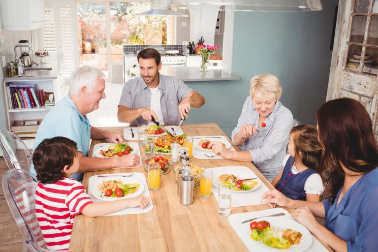 Mehrgenerationenfamilie beim gemeinsamen Mittagessen in gemütlicher Wohnküche – Symbol für familiären Zusammenhalt und Lebensqualität im eigenen Zuhause.
