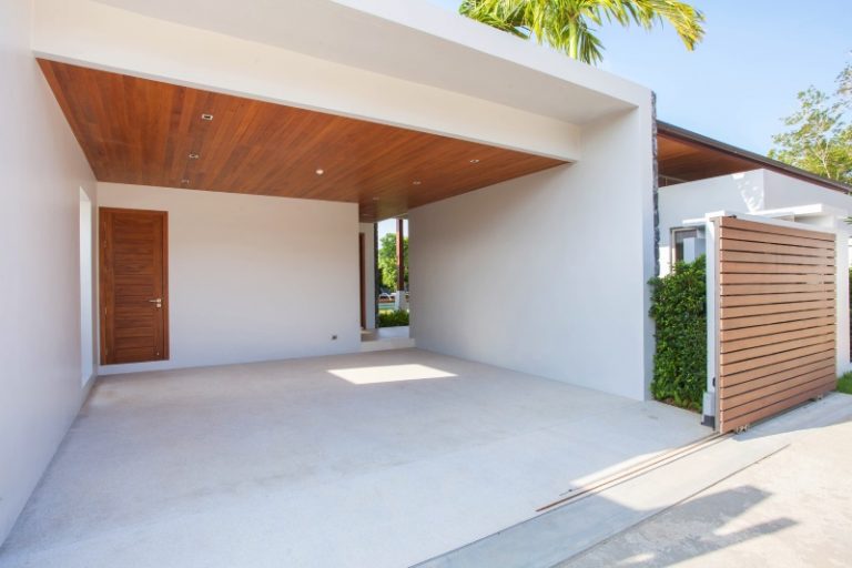 Moderne offene Garage mit weiß verputzten Wänden, Holzdecke mit Einbauspots und angrenzendem Sichtschutzzaun aus Holzlamellen.