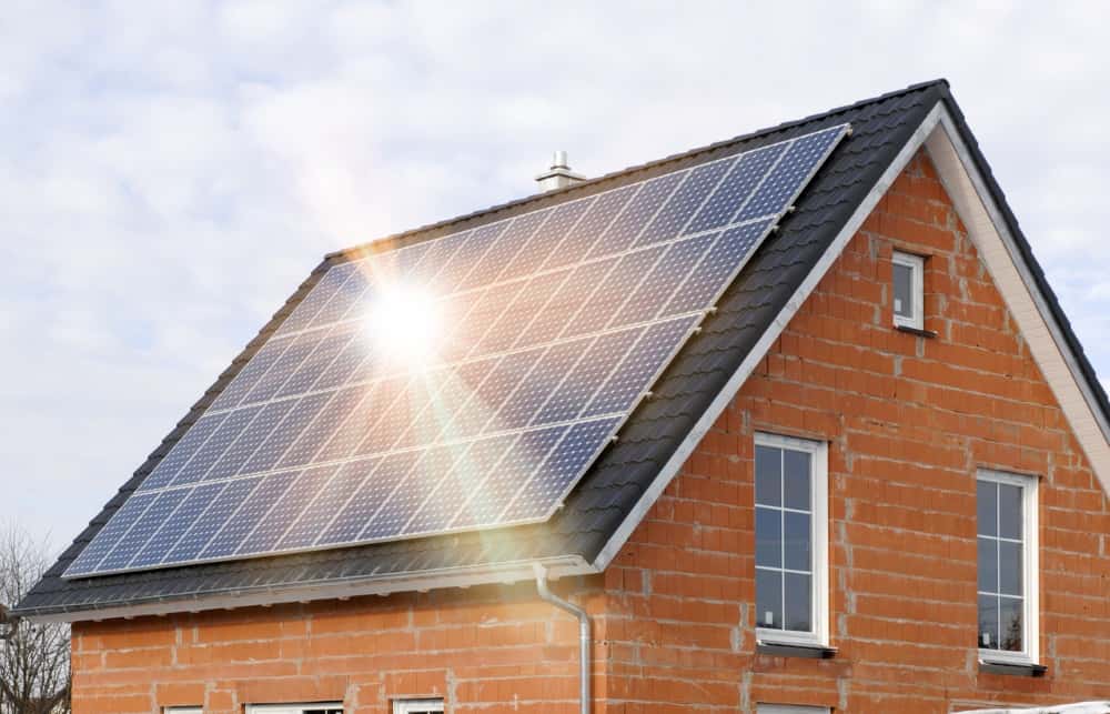 Dach eines Neubaus mit installierter Photovoltaikanlage, Sonnenstrahlen spiegeln sich auf den Solarpanels, symbolisch für nachhaltige Energiegewinnung.