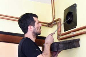 Schornsteinfeger führt eine Feuerstättenschau an einer Heizungsanlage durch.