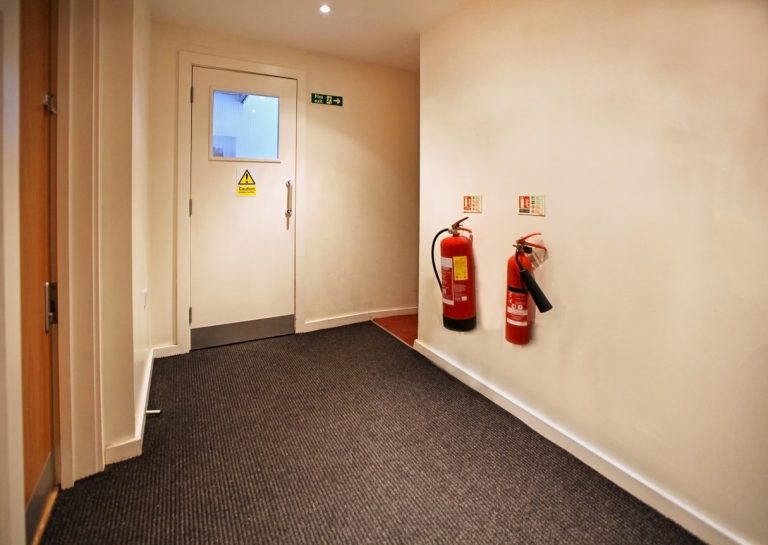 Notausgang mit Brandschutztür und Feuerlöschern an der Wand