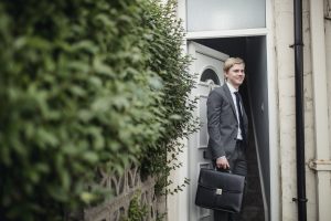 Kaufmann mit Aktentasche verlässt Zweitwohnung für Arbeit