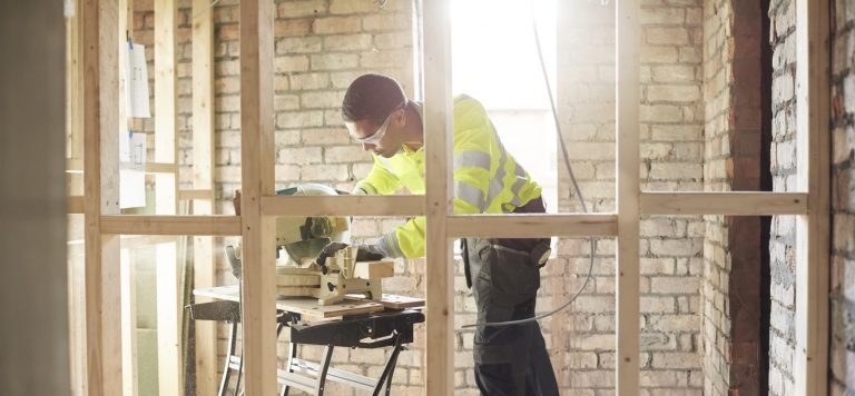 Handwerker baut Trockenwand aus Holz in altes Mauerwerk