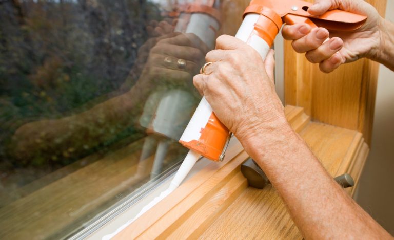 Fensterbauer dichtet Fenster mit Silikon ab