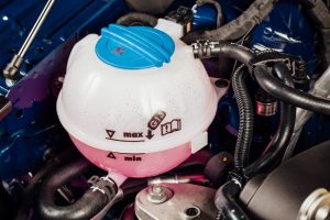 Kühlwasserbehälter mit rosa Kühlwasser im Motorblock eines Autos