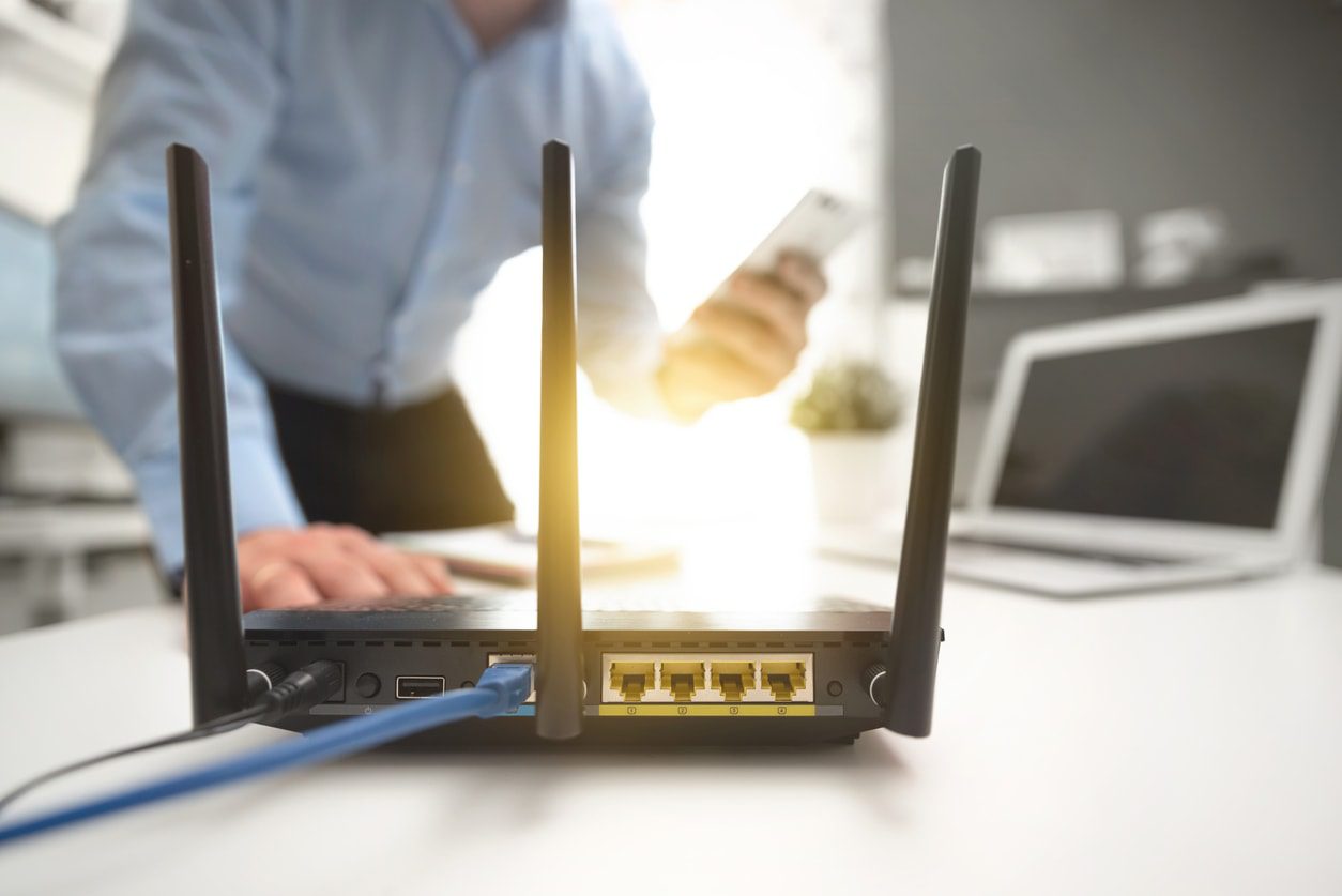 Mann mit Handy prüft WLAN Router