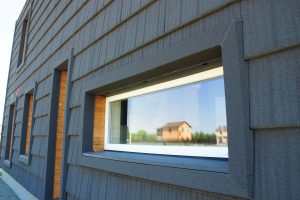 Frontansicht eines Hauses mit Holzverkleidung und einem Passivhausfenster.
