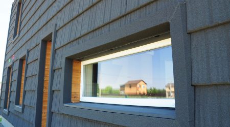 Frontansicht eines Hauses mit Holzverkleidung und einem Passivhausfenster.