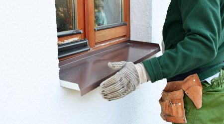 Fensterbauer montiert äußere Fensterbank an einem Holzfenster