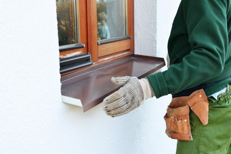 Fensterbauer montiert äußere Fensterbank an einem Holzfenster