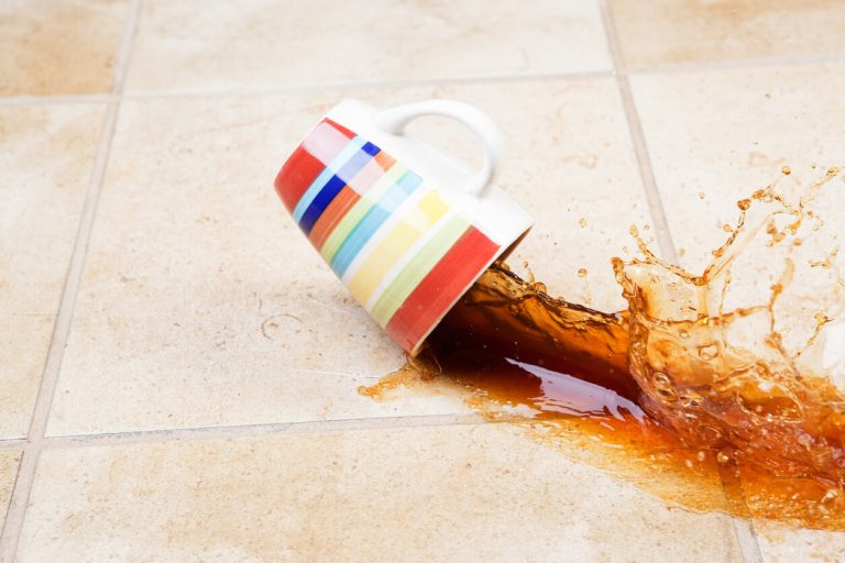 Kaffeetasse fällt auf Fliesenboden