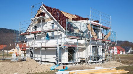 Ein Einfamilienhaus mit einem Fassadengerüst auf einer Baustelle.