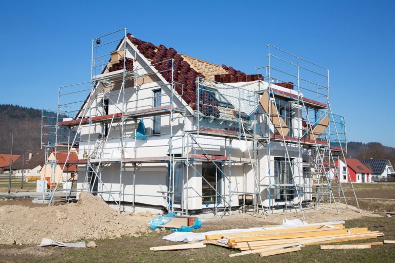 Ein Einfamilienhaus mit einem Fassadengerüst auf einer Baustelle.