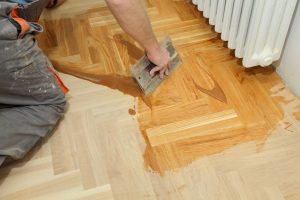 Auftragen der Versiegelung eines Dielenbodens mit einer Spachtel