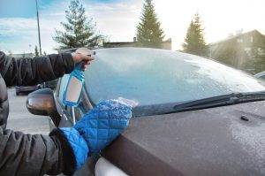 Person beim Enteisen einer Autoscheibe