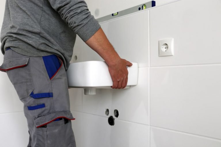 Handwerker montiert neues Waschbecken im Badezimmer