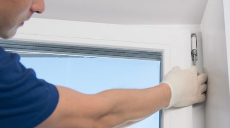 Fensterbauer beim Fenster aushängen mit weißen Handschuhen