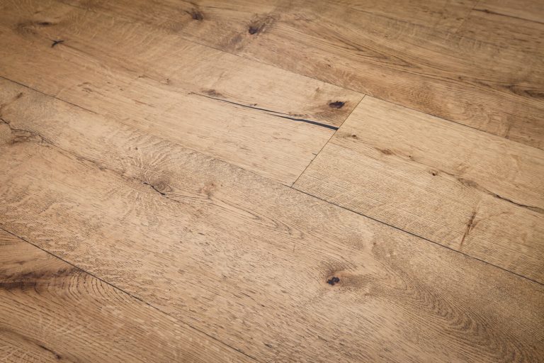 Nahaufnahme eines rustikalen Eichenparketts mit natürlicher Maserung, Astlöchern und Fasen – ideal für ein wohnliches, warmes Raumklima.