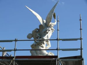 Skulptur mit Engelsfigur auf einem Arbeitsgerüst unter freiem Himmel während Restaurierungsarbeiten.