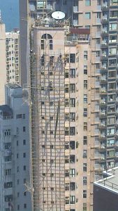 Hochhaus mit traditionellem Bambusgerüst an der Fassade für Bau oder Instandhaltungsarbeiten in einer asiatischen Großstadt.