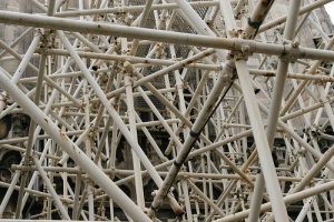 Komplexes Bockgerüst aus Metallrohren mit zahlreichen diagonalen und vertikalen Verbindungen vor einer historischen Fassade.